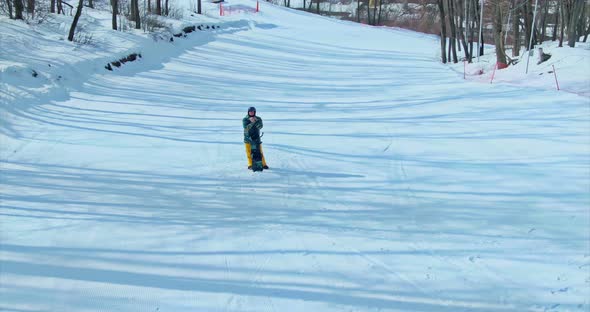 Man Stands in the Snow with a Snowboard Examines the Surroundings