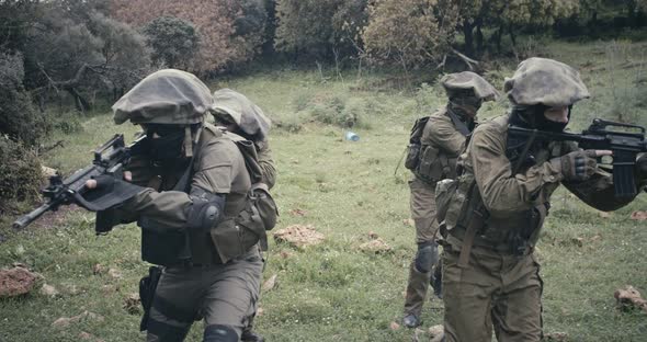 Squad of fully armed commando soldiers during combat in a forest scenery