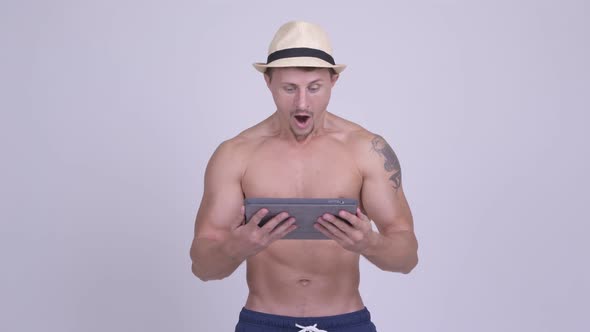 Happy Muscular Bearded Tourist Man Using Digital Tablet and Getting Good News