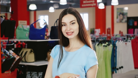 Portrait Of An Attractive Brunette With Shopping Bags. Smiling, Looking At The Camera