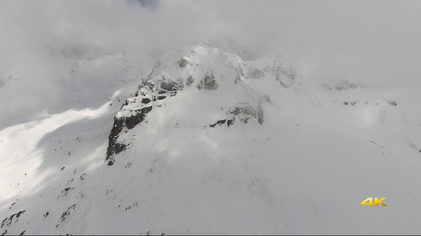 Aerial Snowy Mountain Peaks Through the Clouds