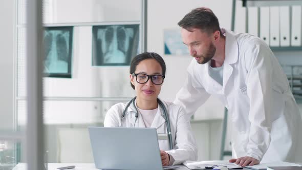 Professional Male and Female Doctors Smiling at Camera in Medical Office