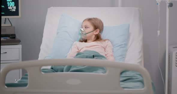 Girl Suffering From Pneumonia Lying in a Hospital Bed with Oxygen Mask