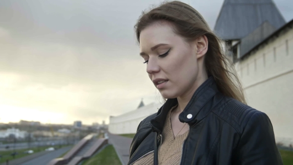 Cute Girl With Long Blonde Hair In Leather Jacket Straightens Hair Looking To The Sky