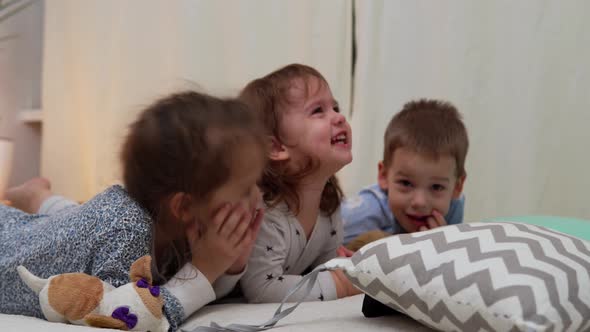 Smiling Preschool Toddler Children In Pajamas Watching Cartoon on Smartphone on Bed