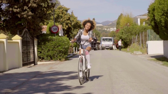 Young Woman Riding The Bicycle On The Road