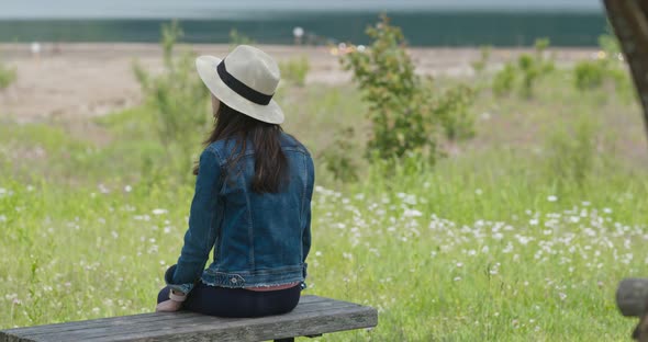 Woman look around the landscape and sit on the wooden bench