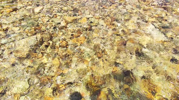 Close-up of the water surface and yellow and broun stones