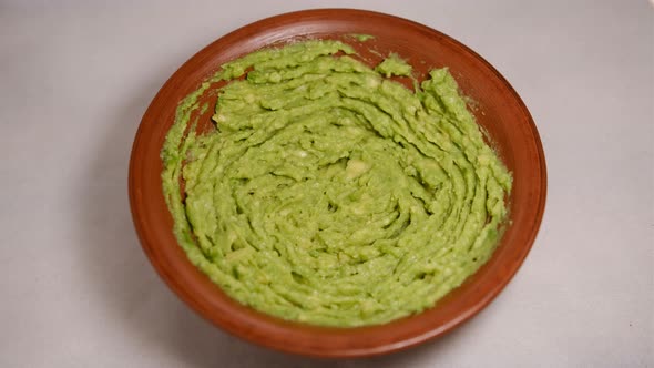 Extreme closeup top view of avocado smash rotating. Traditional tasty sauce guacamole. Adding onion