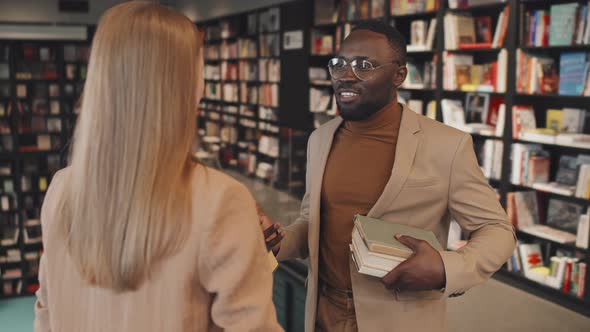 African American Man Talking to Woman in Library