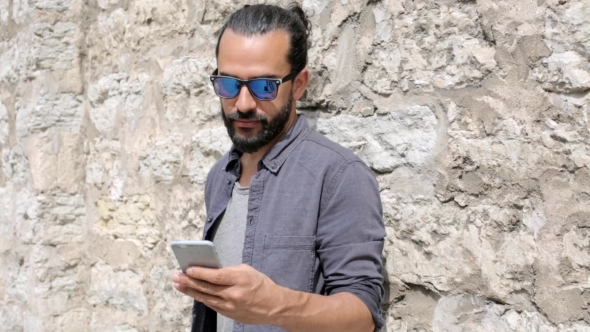 Man Texting Message On Smartphone At Stone Wall 2