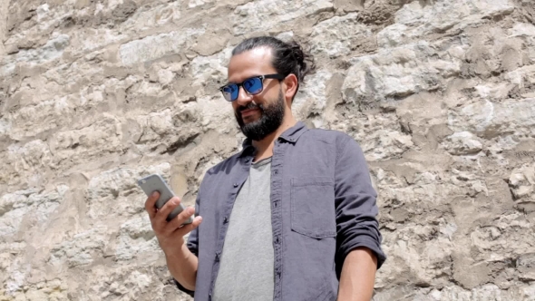 Man Texting Message On Smartphone At Stone Wall 4