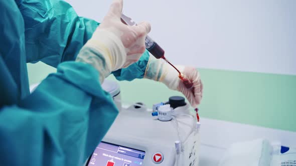 Stem cells injection procedure. Female worker pours blood from syringe into special machine.