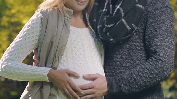 Pregnant Couple Posing for Camera in Autumn Park