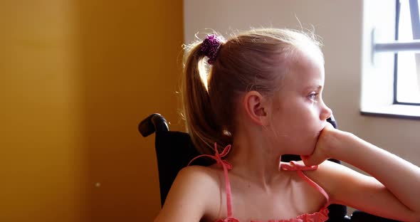 Disabled school girl looking through window in classroom