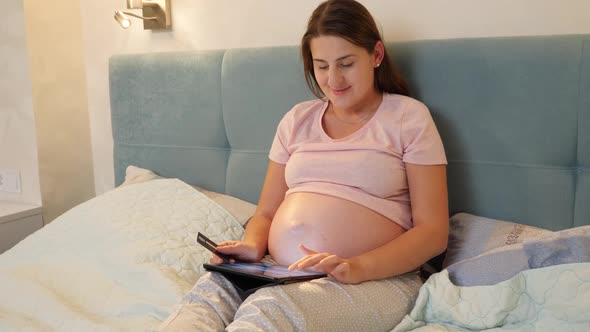 Beautiful Pregnant Woman Paying with Credit Card While Doing Online Purchase in Store