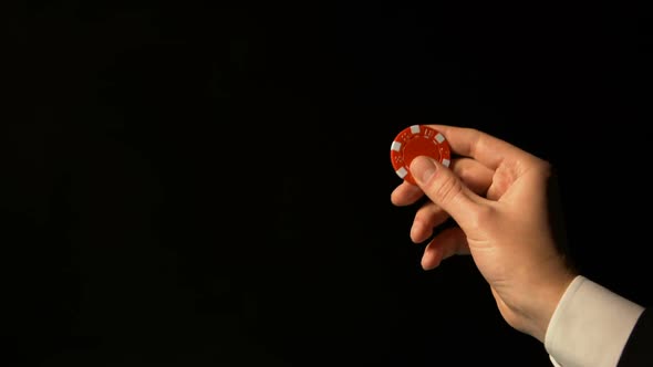 Hand in Suit Showing Red Chip Against Black Background, Successful Poker Bets