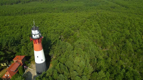 The drone slow pulls out and reveals Stilo Lighthouse and green forest around it - lighthouse locate