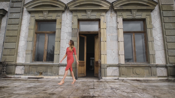 Attractive Girl In Red Dress Goes On The Balcony Of An Old Manor.