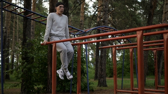 Young Man Doing Exercise At The Horizontal Bar In The Evening