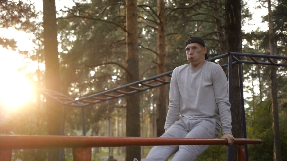 Young Man Doing Exercise At The Horizontal Bar In The Evening