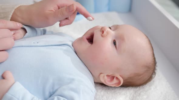 Cute Little Baby Boy Lying on Dressing Table While Mother Applying Moisturizing and Cleaning Creme