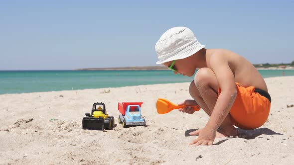 on a Sunny Summer Day a Child a Boy Playing with Sand and Toys Cars on the Beach Azure Sea and Blue