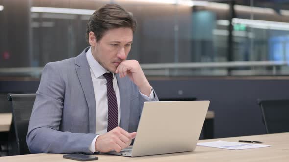 Middle Aged Businessman with Laptop, Thinking in Office 