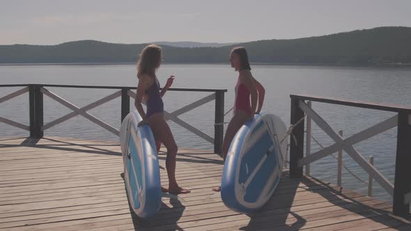 Girlfriends Talking at Pier with Paddleboards
