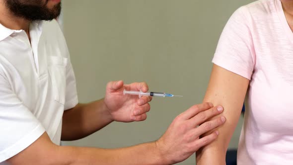 Male therapist injecting female patient