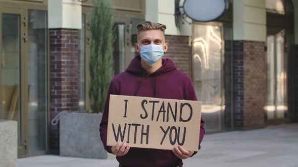 Caucasian Male Protester Activist Wearing a Medical Mask Holds a Cardboard Poster with the Slogan I