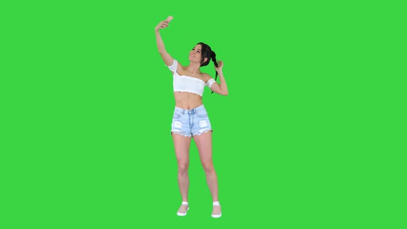 Cute Brunette Girl Takes a Selfie and Dancing on a Green Screen, Chroma Key.