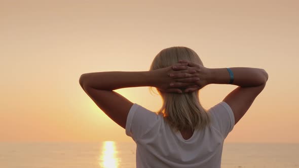 A Young Fair-haired Tourist Meets the Dawn on the Seashore, Relaxes, Enjoys the Silence. View From