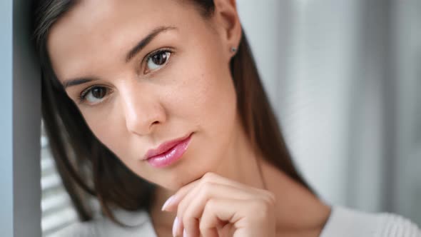 Closeup Face of Pensive Young Casual Female Standing Near Window