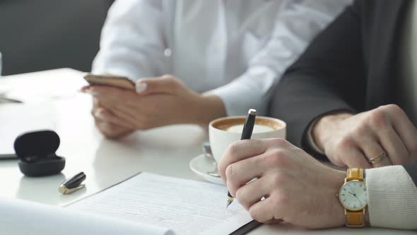 Woman Explains a Business Idea to a Colleague Shows Something on a Smartphone Sits in a Cafe Talks