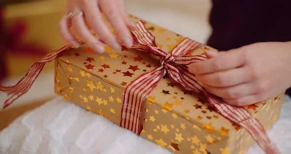 Midsection Of Woman Tying Ribbon On Christmas Present