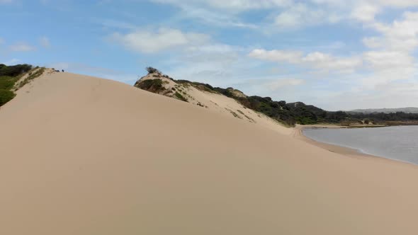 A fast moving forward aerial of a river mouth system and moving over the sand dunes to reveal the oc