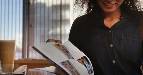 Woman reading magazine while having coffee