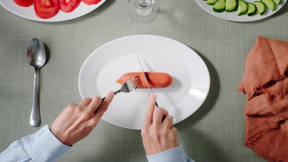 a Restaurant Visitor Cuts a Sausage on His Plate with a Knife and Fork