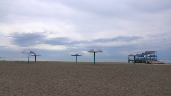 Empty Sandy Beach And Big Sun Umbrellas On a Cloudy Day