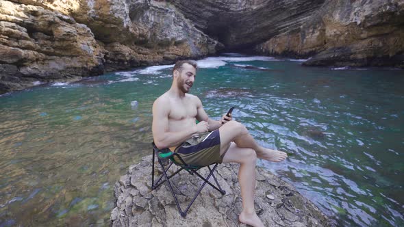 The man is talking on the phone in the sea zone.