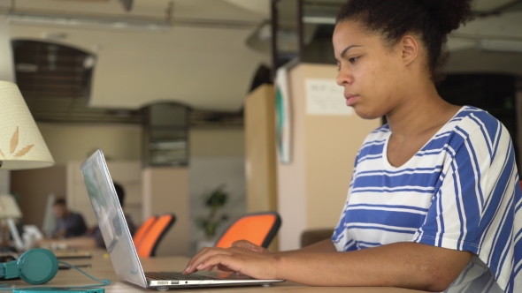 Happy Mixed Race Woman Typing On The Computer At The Working Place.