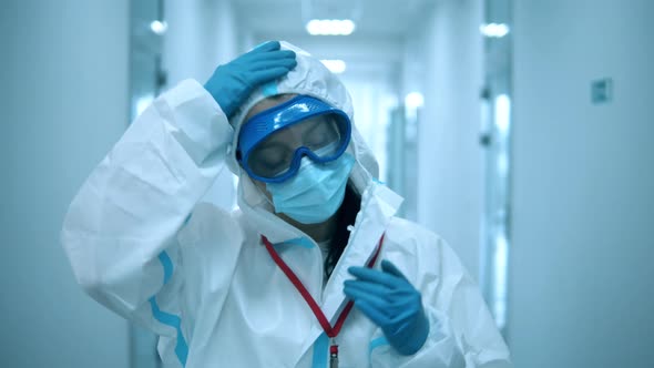 Female Doctor Takes Off Face Mask After a Working Day at Clinic.