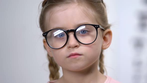 Female Child in Eyeglasses Covering Eye Examination Tool