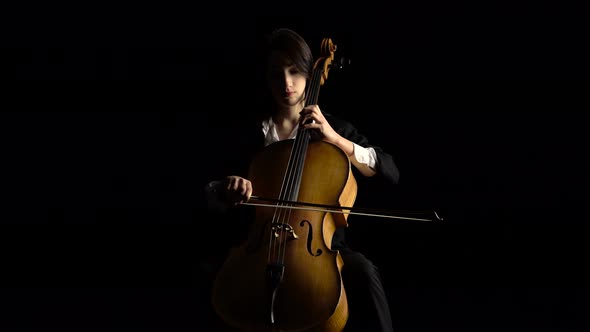 Girl Plays the Cello on Dark Studio. Black Background