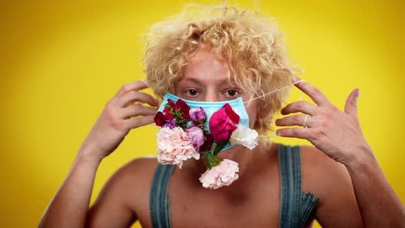 Portrait of Confident Sad Caucasian LGBT Man Putting on Coronavirus Flower Face Mask Looking at