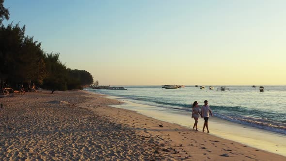 Boy and girl posing on luxury seashore beach voyage by blue sea with white sandy background of Gili 