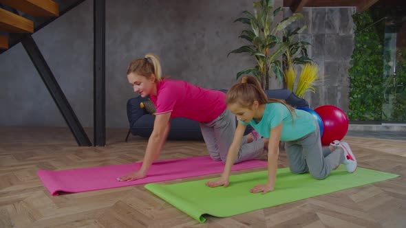 Fitness Mom with Child Performing Plank Exercise Indoors