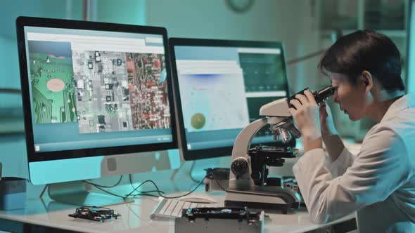 Female Engineer Examining Computer Chip with Microscope