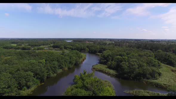 Flying Over a Small River with Tributaries Surrounded By Forest